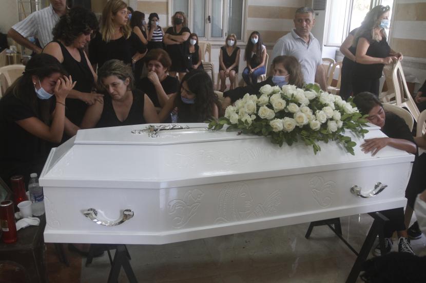  Kerabat Nicole al-Helou, yang tewas dalam ledakan Selasa yang menghantam pelabuhan Beirut, berduka di samping peti matinya saat pemakamannya, di desa Sarba, Lebanon selatan, Kamis, 6 Agustus 2020.