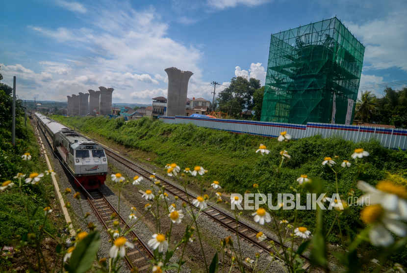 Kereta api melintas di samping proyek pembangunan jalur kereta cepat Jakarta-Bandung di Cipatat, Kabupaten Bandung Barat, Jawa Barat.