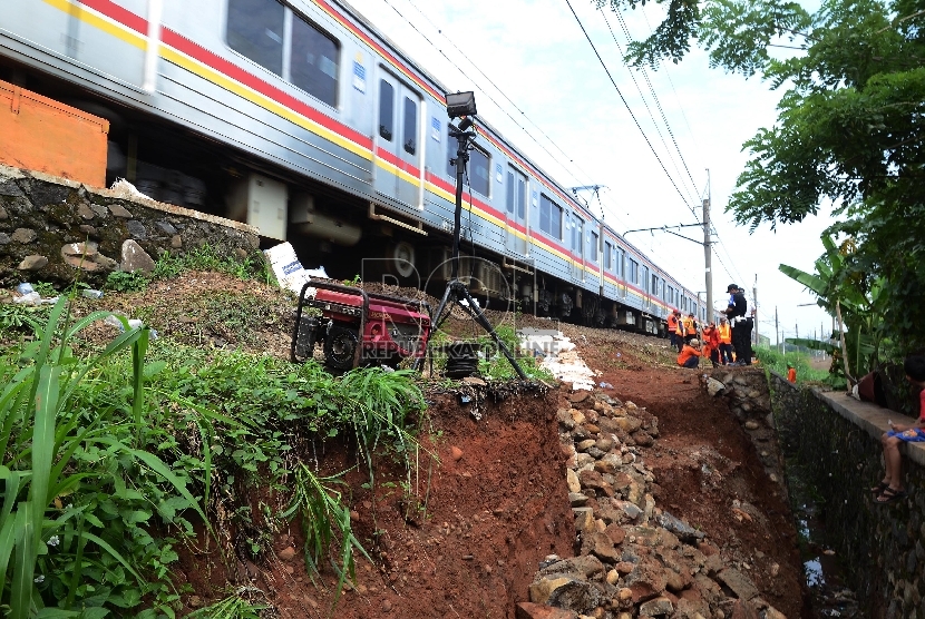 Kereta Commuter Line (KRL) dari Bogor menuju Jakarta berjalan perlahan saat melintasi longsoran pinggir rel di dekat Stasiun Citayam, Depok, Rabu (25/11).