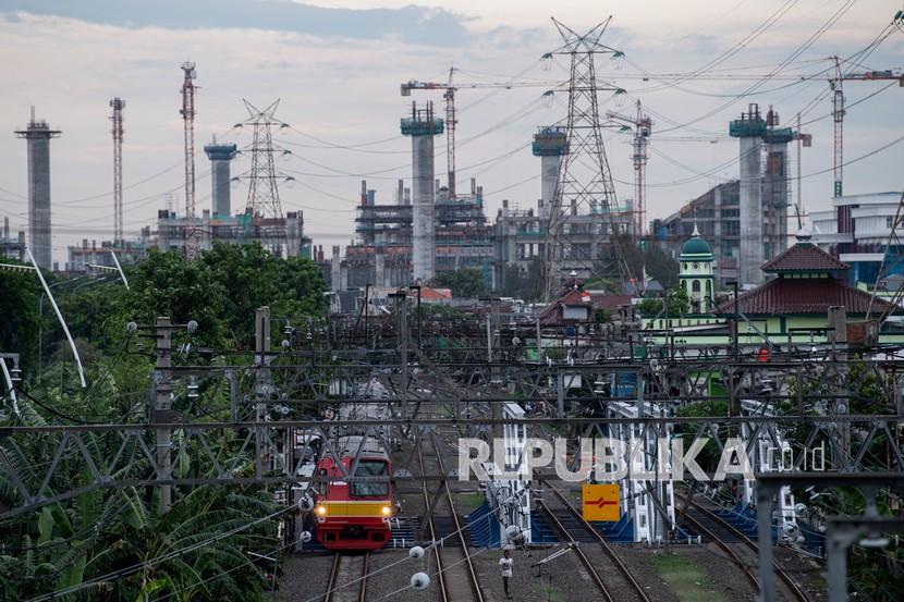 KRL Commuter Line melintas dengan latar belakang pembangunan Jakarta International Stadium (JIS) di Tanjung Priok, Jakarta Utara.