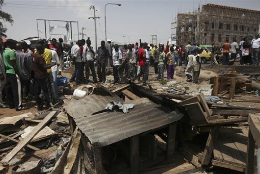 Kerumunan orang yang menyaksikan kerusakan akibat ledakan bom di Kaduna, Nigeria, Senin (9/4).