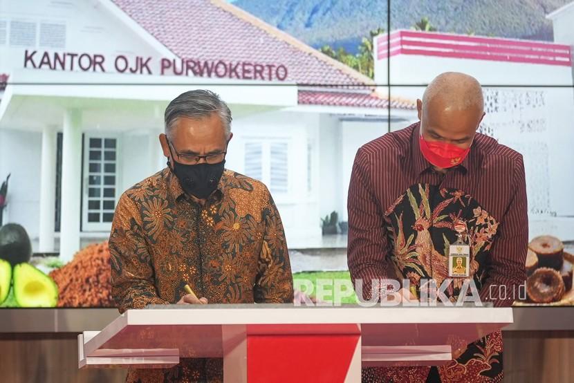 Ketua Dewan Komisioner Otoritas Jasa Keuangan (OJK) Wimboh Santoso (kiri) bersama Gubernur Jateng Ganjar Pranowo (kanan) menandatangani prasasti peresmian Kantor OJK Purwokerto, Banyumas, Jateng, Selasa (8/3/2022). 