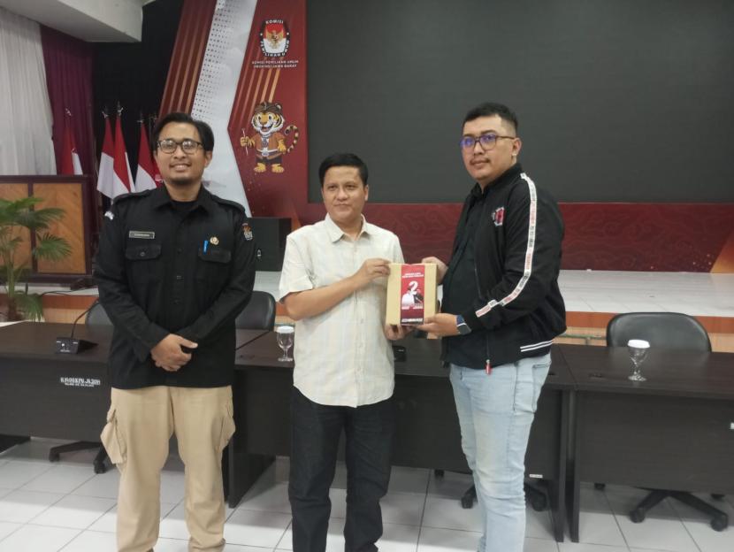 Ketua Divisi Sosialisasi Pendidikan Pemilih dan Partisipasi Masyarakat KPU Jabar, Hedi Ardia menyerahkan APK kepada perwakilan tim paslon Cagub-Cawagub Jabar 2024 di Aula Setia Permana, Kantor KPU Jabar.