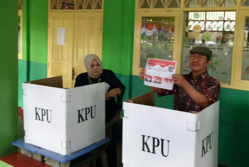 Ketua DKPP, Jimly Asshiddiqie (kanan) dan sang istri (kiri) sedang berada dibalik suara di TPS 021 Pondok Labu, Jakarta Selatan, Rabu (15/2). 