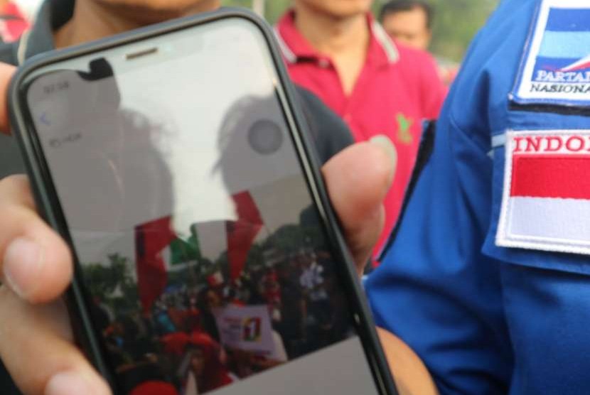 Ketua DPP Partai Demokrat Ferdinand Hutahaean menunjukan foto sejumlah massa yang membawa bendera bertuliskan Projo yang membuat Ketua Umum Partai Demokrat Susilo Bambang Yudhoyono (SBY) walkout dari karnaval kampanye damai di Silang Monas, Jakarta, Ahad (23/9). 