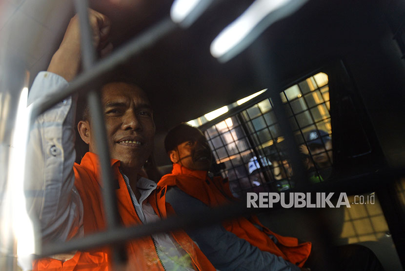 Ketua DPRD Kota Malang, Abdul Hakim (kiri) dan anggota DPRD Kota Malang Imam Fauzi mengangkat tangan ketika menaiki mobil tahanan seusai menjalani pemeriksaan di gedung KPK, Jakarta, Jumat (6/4). 