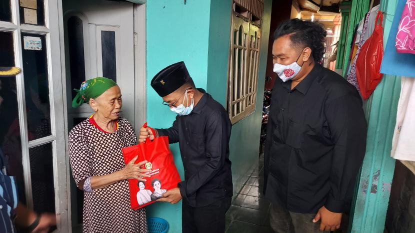 Ketua DPRD Kota Tangerang Gatot Wibowo  disampingi sekretaris DPC PDI P kota Tangerang Andry S Permana saat memberikan bantuan sembako ke warga di Karang Tengah,  Ahad (29/8).