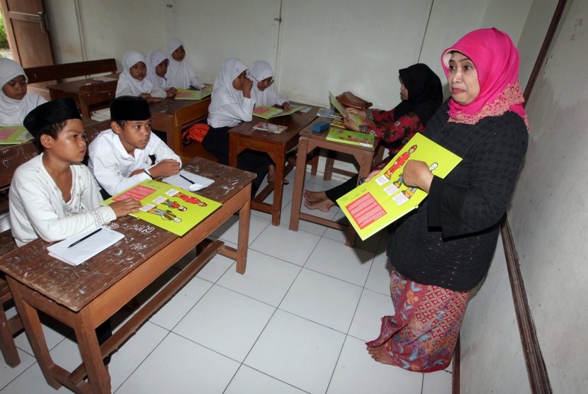 Ketua Himpunan Wanita SKK Migas (HWS) Luthfia Amien Sunaryadi (kanan) memberikan penjelasan tentang buku migas kepada siswa-siswi Madrasah Diniyah Awaliyah di Kampung Sukadiri, Kota Serang, Banten, Rabu (16/3).