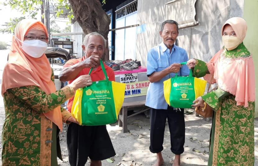 Ketua Ikatan Istri Karyawan dan Karyawati Unissula (IIKKU) Dra Ida Rahmawati (kiri) menyerahkan bantuan paket sembako kepada warga kurang mampu di sekitar kampus Unissula Semarang, Kamis (14/4).