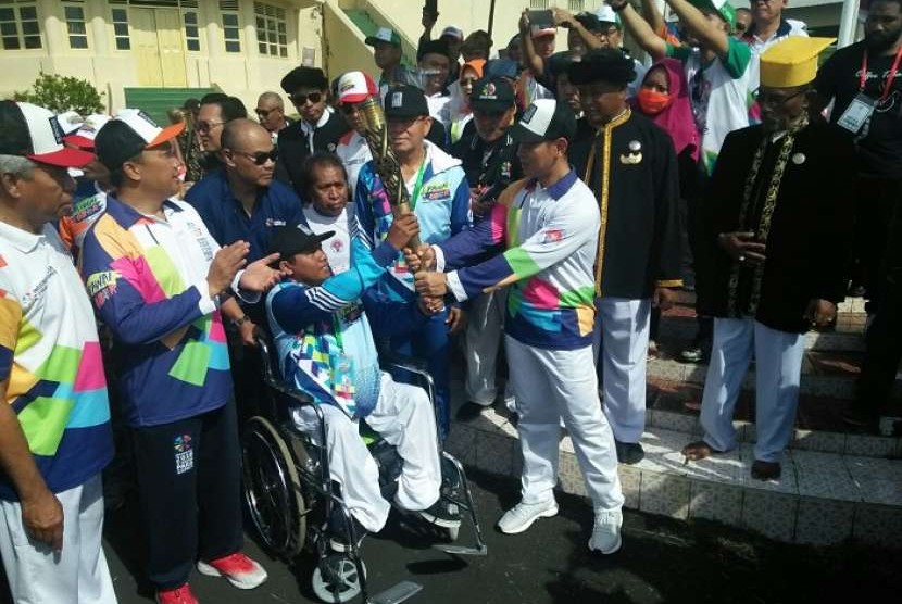 Ketua Inapgoc Raja Sapta Oktohari menyerahkan obor Asian Para Games 2018 kepada atlet difabel Ternate Risal Assor di halaman Kedaton Sultan Ternate, Ahad (9/9).