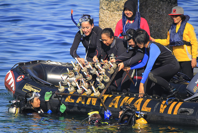 Ketua Kongres Wanita Indonesia (Kowani) (kiri) Giwo Rubianto Wiyogo bersama sejumlah perempuan mengangkat terumbu karang yang akan dilepaskan ke dalam laut di Kupang, NTT Jumat (11/12).