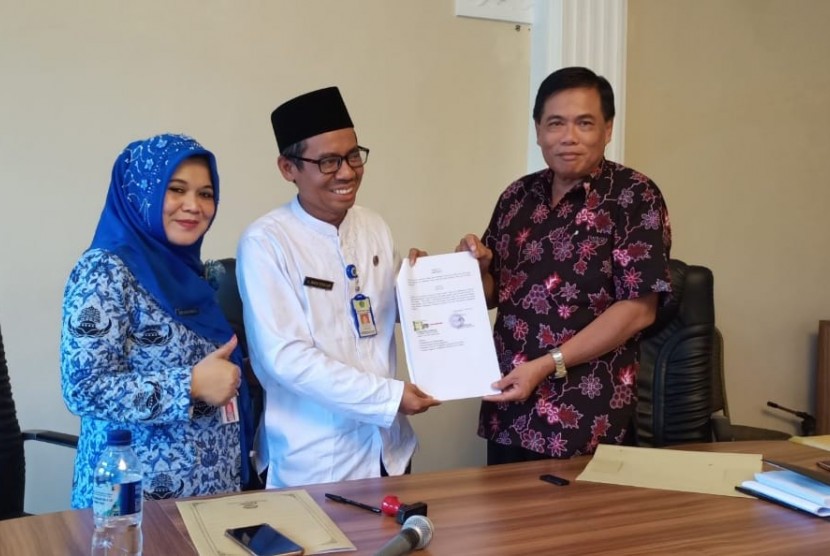 Ketua Koperasi Amal Bakti Kemenag Kabupaten Banjarnegara, M  Setiadi  SPd (kanan) dan Kepala Perwakilan Naja Travel Banjarnegara,  KH  Nafis Attaillah MA Alhafizh (tengah) menandatangani kerja sama (MoU).