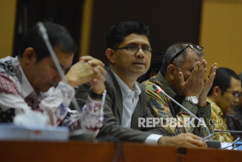 Ketua KPK Agus Raharjo (kanan) memengusap wajahnya bersama dengan Wakil Ketua KPK Laode M. Syarif (tengah) yang tengah memberikan pemaparan saat Rapat Dengar Pendapat (RDP) bersama Komisi II di Kompleks Parlemen, Jakarta, Rabu (15/6).  