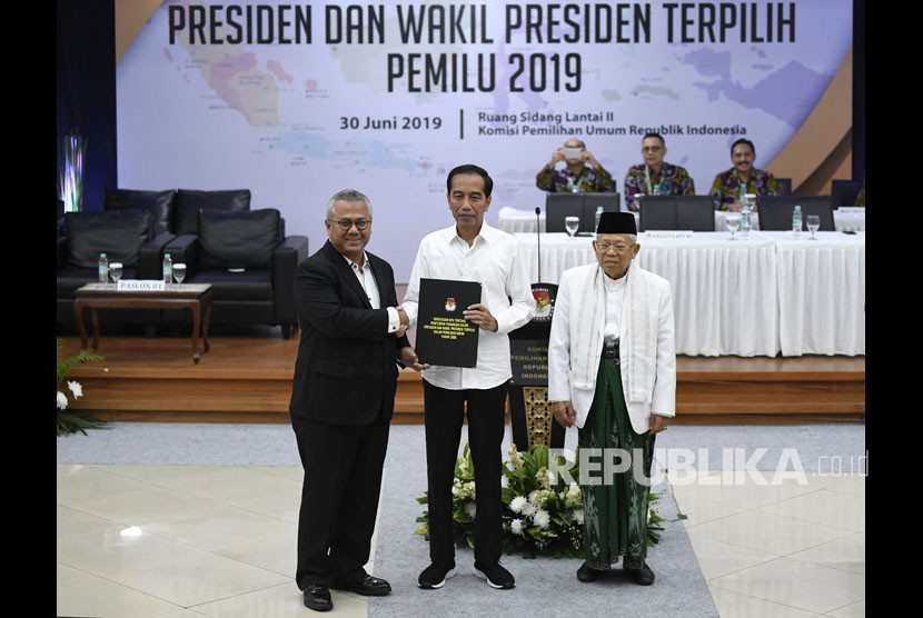 Ketua KPU Arief Budiman (kiri) menyerahkan surat keputusan KPU tentang Penetapan Hasil Pemilu 2019 kepada Presiden dan Wakil Presiden terpilih periode 2019-2024, Joko Widodo (tengah) dan KH Ma'ruf Amin (kanan) di gedung KPU, Jakarta, Ahad (30/6/2019). 