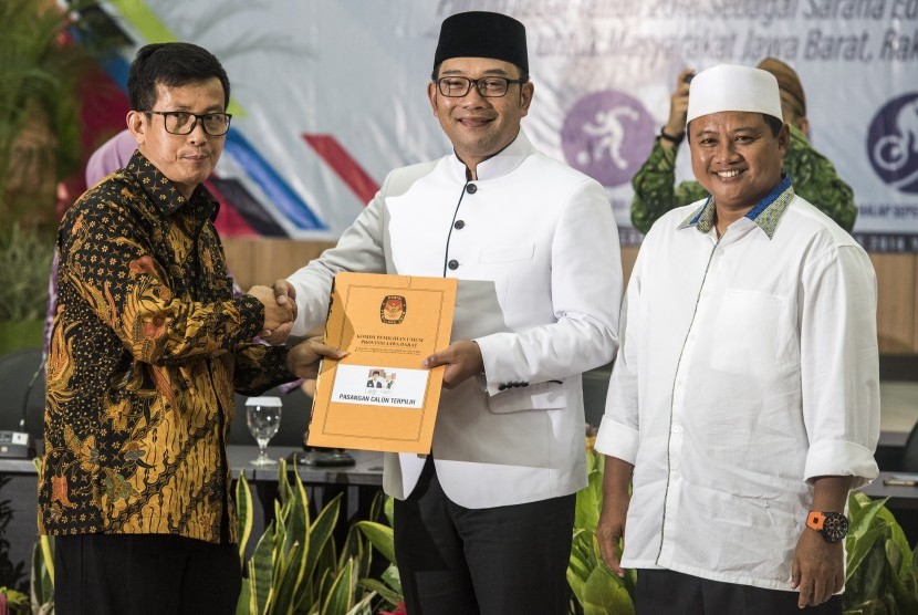 Ketua KPU Jabar Yayat Hidayat (kiri) memberikan berkas berita acara dan surat keputusan kepada pasangan Gubernur dan Wakil Gubernur Jawa Barat terpilih Ridwan Kamil (tengah) dan Uu Ruzhanul Ulum (kanan) saat rapat pleno terbuka Penetapan Pasangan Calon Terpilih pada Pilgub Jabar 2018 di Bandung, Jawa Barat, Selasa (24/7). 