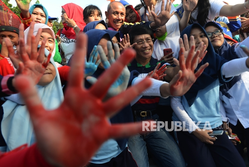 Ketua Lembaga Perlindungan Anak Indonesia (LPAI), Seto Mulyadi (tengah) bersama siswa menunjukan tangan kirinya seusai memberikan cap tangan di kain putih saat berlangsungya acara Stop Stigma di Gerbang Monas, Jakarta, Ahad (12/3).