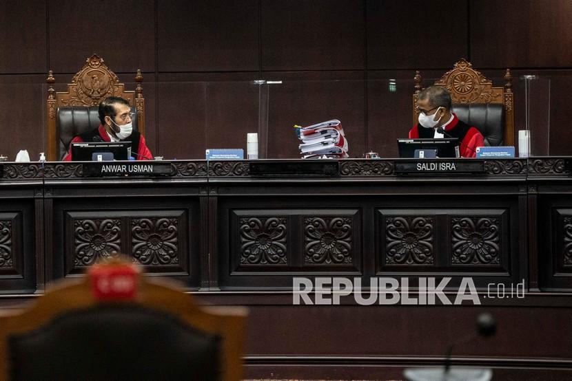 Ketua Majelis Hakim Mahkamah Konstitusi (MK) Anwar Usman (kiri) berbincang dengan anggota Majelis Hakim MK Saldi Isra dalam sidang lanjutan pengujian formil dan materiil Undang-Undang Nomor 11 Tahun 2020 tentang Cipta Kerja terhadap UUD 1945 di Ruang Sidang Gedung MK, Jakarta, Rabu (13/10/2021). Sidang tersebut beragenda mendengarkan keterangan ahli yang dihadirkan DPR. 