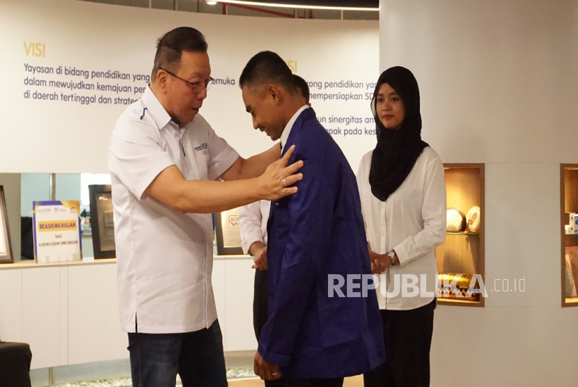 Ketua Pengurus Yayasan Astra - Yayasan Pendidikan Astra Michael D. Ruslim, Gunawan Salim (pertama dari kiri) mengenakan almamater ASTRAtech untuk salah satu siswa SMK binaan yang menerima beasiswa, Rudi Nur Hidayanto.