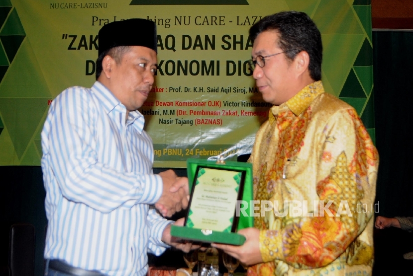 Ketua PP Lazis NU Syamsul Huda (kiri) menyerahkan cendera mata kepada Ketua Dewan Komisioner OJK Muliaman D Hadad pada acara Seminar Pra-Launching NU Care Laziznu, dengan tema “Zakiat, Infak, dan Sedekah di Era Ekonomi Digital” di Jakarta, Rabu (24/2).