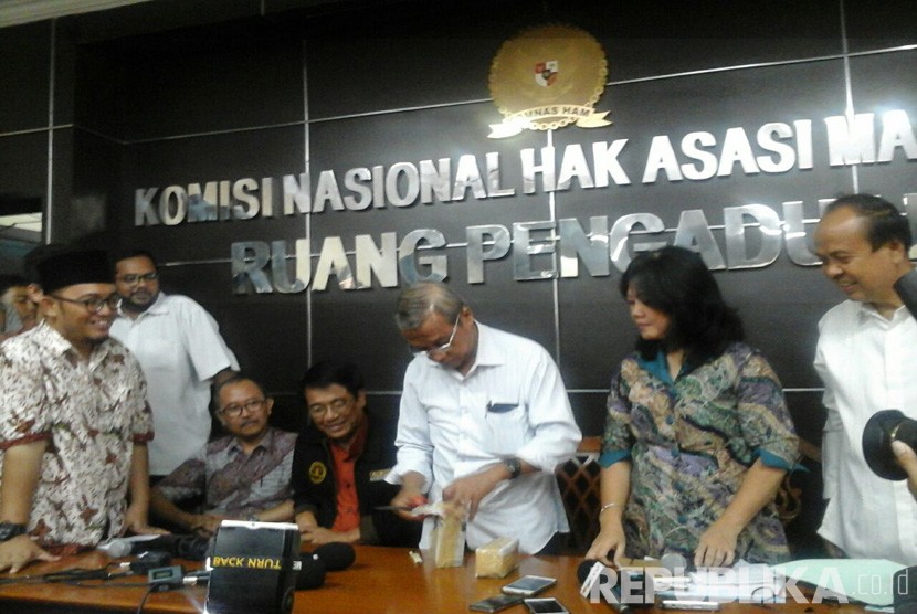 Ketua PP Muhammadiyah bidang hukum, Busyro Muqoddas saat membuka bungkusan uang pemberian Densus 88 untuk isteri almarhum Siyono, Suratmi.