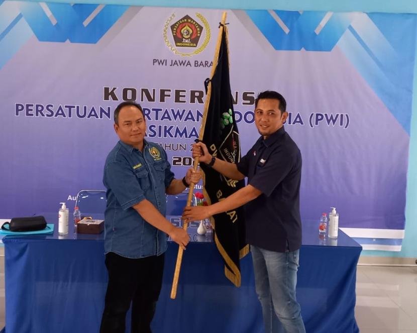 Ketua PWI Jabar Hilman Hidayat (kiri) menyerahkan bendera pataka kepada Ketua PWI Tasikmalaya terpilih Asep Juharyono usai konferensi PWI Tasikmalaya di Aula PWI Jabar, Senin (7/8/2023).