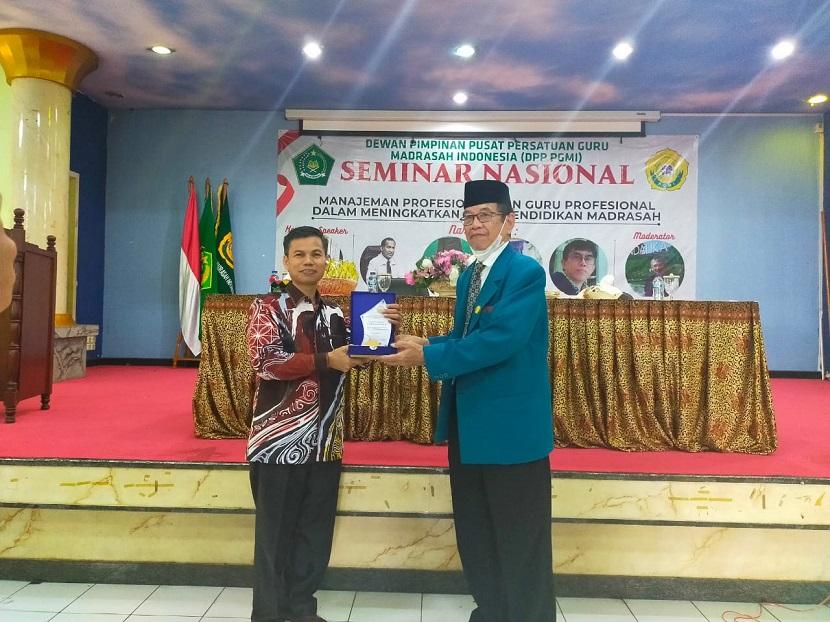 Ketua Umum DPP PGMI Drs H Syamsuddin, MPd memberikan plakat kepada salah satu pembicara dalam  Seminar Nasional  