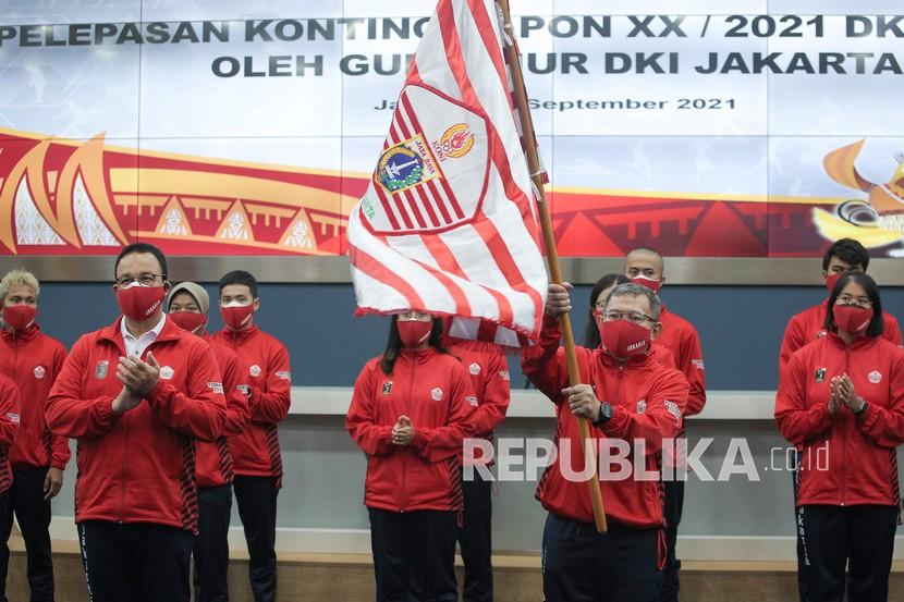 Ketua Umum KONI DKI Jakarta Djamhuron Wibowo (kanan) mengibarkan bendera bersama Gubernur DKI Jakarta Anies Baswedan (kiri).