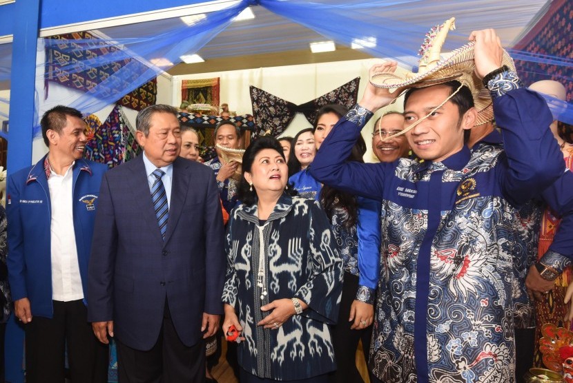 Ketua Umum Partai Demokrat Susilo Bambang Yudhoyono (kedua kiri) dan Ibu Ani Yudhoyono (kedua kanan), memperhatikan Ketua Fraksi Edhie Baskoro Yudhoyono (kanan) mengenakan topi tradisional saat meninjau stan daerah sebelum menghadiri puncak peringatan HUT 