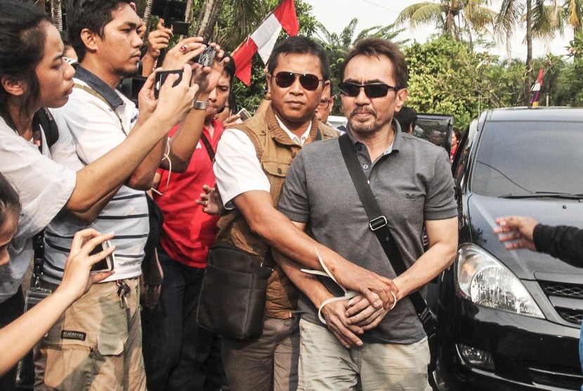 Ketua Umum Persatuan Artis Film Indonesia (PARFI) Gatot Brajamusti alias AA Gatot (kanan) dikawal petugas saat tiba di rumahnya di kawasan Pondok Indah, Jakarta, Kamis (1/9).