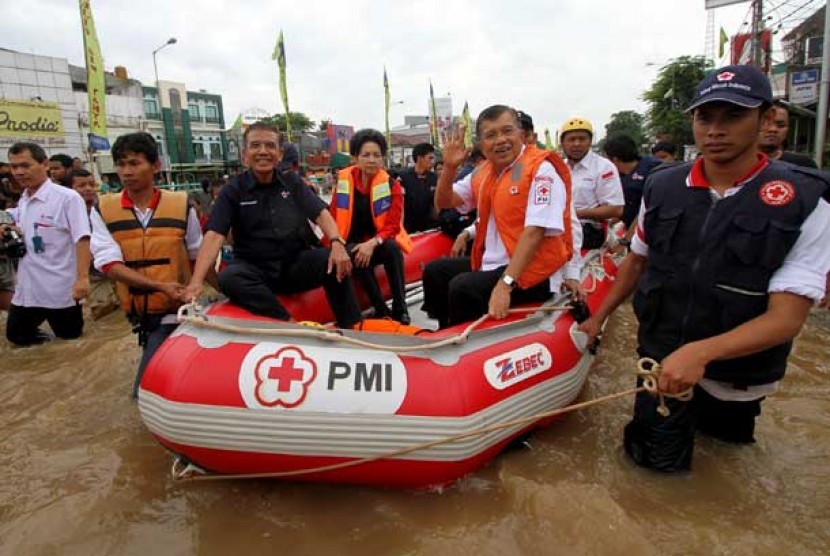  Ketua Umum PMI Jusuf Kalla didampingi pengurus PMI menggunakan perahu karet meninjau lokasi banjir di kawasan Kampung Melayu Besar, Jakarta, Rabu (16/1). 