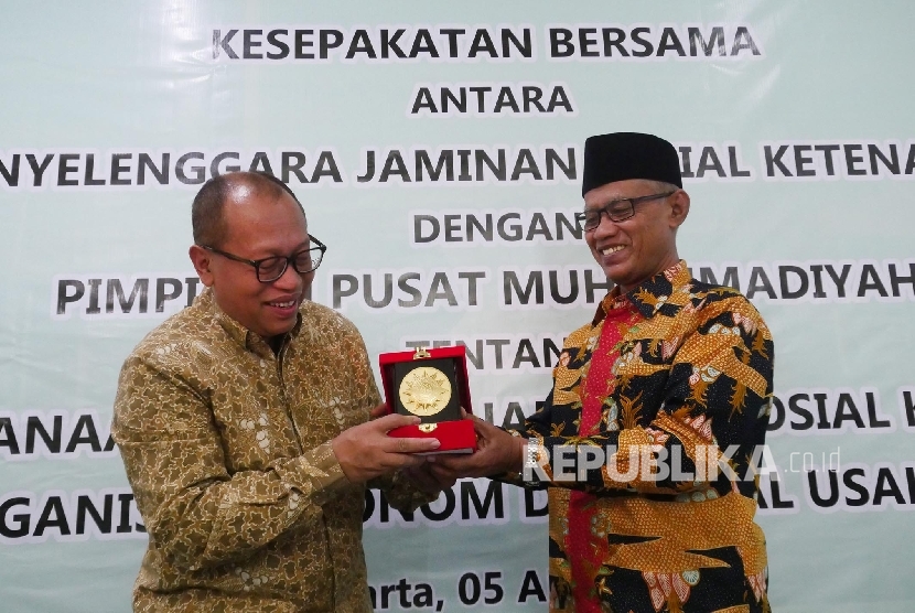  Ketua Umum PP Muhammadiyah Haedar Nashir (kiri) menyerahkan cinderamata kepada Direktur Utama BPJS Ketenagakerjaan Agus Susanto usai acara penendatangan kerjasama antara BPJS Ketenagakerjaan dan Muhammdiyah di Jakarta, Rabu (5/4). 