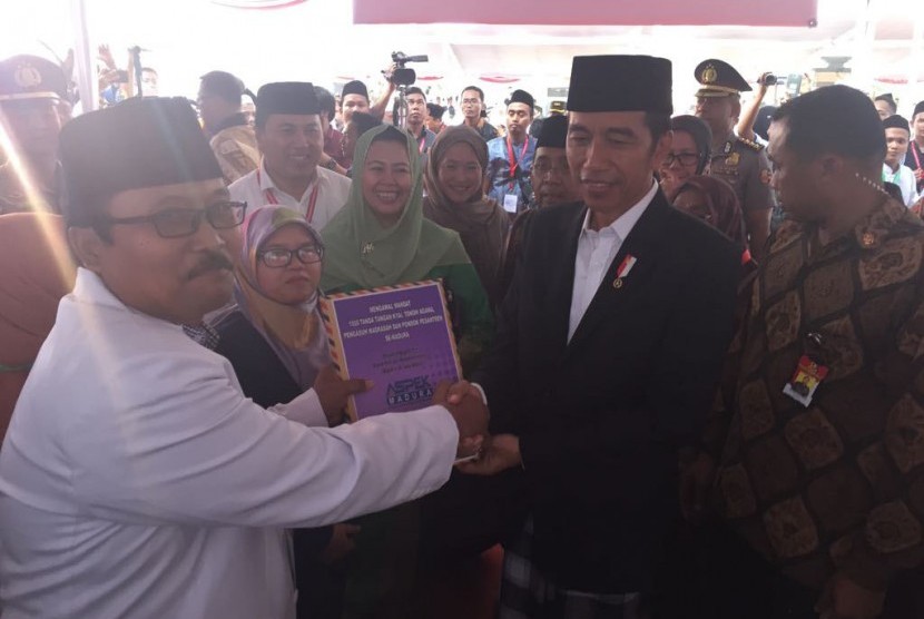 KH. Muchlis Muchsin (sebelah kiri) menyerahkan surat mandat 1000 tanda tangan kyai dan pengasuh pondok pesantren, pengasuh madrasah dan guru ngaji se-Madura kepada Presiden Jokowi (sebelah kanan).