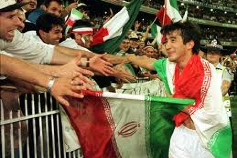 Khodadad Azizi, 'sang pahlawan', merayakan kemenangan atas Australia di playoff Piala Dunia 1998 dengan para suporter Iran.