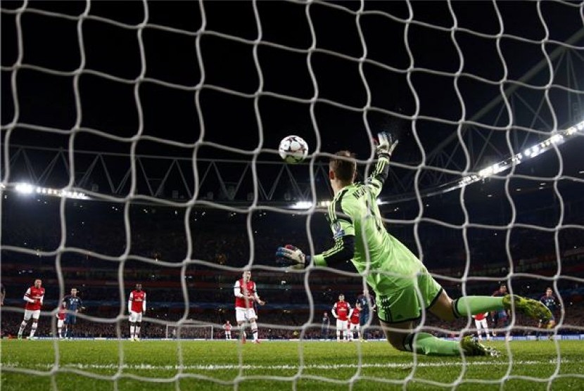 Kiper Bayern Muenchen, Manuel Neuer (kanan), menggagalkan tembakan penalti playmaker Arsenal, Mesut Oezil (tengah), dalam leg pertama babak 16 besar Liga Champions di Stadion Emirates, London, Rabu (19/2). 