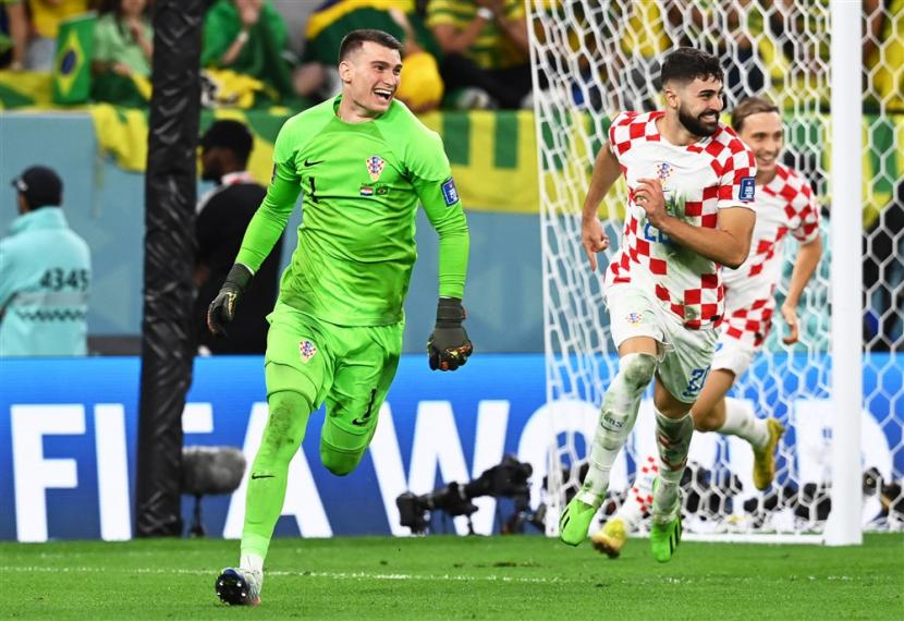  Kiper Kroasia Dominik Livakovic (Kiri) dan rekan setimnya merayakan setelah memenangkan adu penalti pertandingan sepak bola perempat final Piala Dunia 2022 antara Kroasia dan Brasil di Stadion Education City di Doha, Qatar, Jumat (9/12/2022).