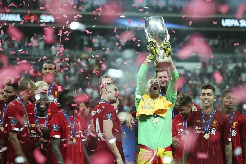 Kiper Liverpool Adrian mengangkat trofi Piala Super Eropa.