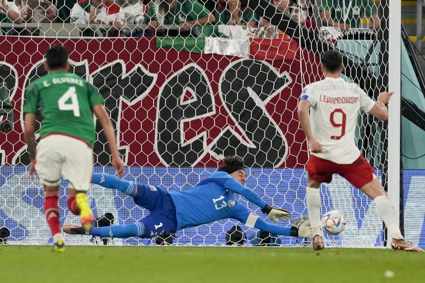 Kiper Meksiko Guillermo Ochoa memblokir tendangan penalti oleh pemain Polandia Robert Lewandowski selama pertandingan sepak bola grup C Piala Dunia antara Meksiko dan Polandia, di Stadion 974 di Doha, Qatar, Selasa, 22 November 2022. 