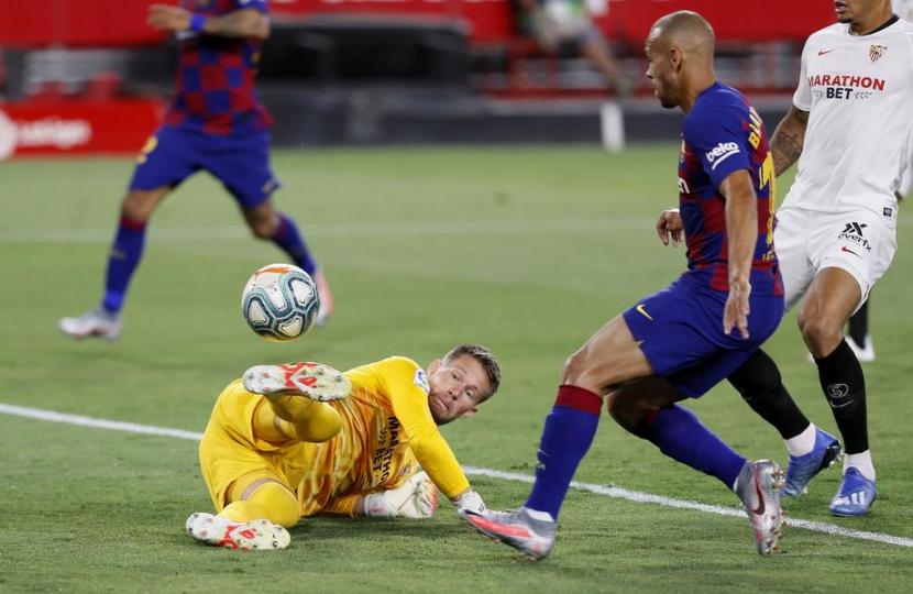 Kiper Sevilla Tomas Vaclik beraksi menggagalkan peluang striker Barcelona Martin Braithwaite dalam pertandingan lanjutan La Liga Spanyol di Stadion Ramon Sanchez Pizjuan, Sevilla, Sabtu (20/6) dini hari WIB.