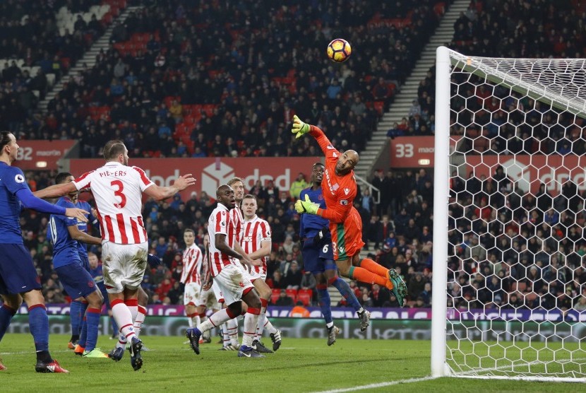 Kiper Stoke City, Lee Grant terbang untuk menghalau tendangan bebas striker Manchester United, Wayne Rooney yang akhirnya berbuah gol. Laga di stadion Bet365 itu berakhir imbang 1-1.