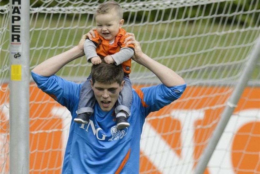 Klaas-Jan Huntelaar, striker timnas Belanda, menggiring bola sambil menggendong anaknya Axel usai menggelar sesi pertama latihan timnas di Lausanne, Swiss, Jumat (18/5).  