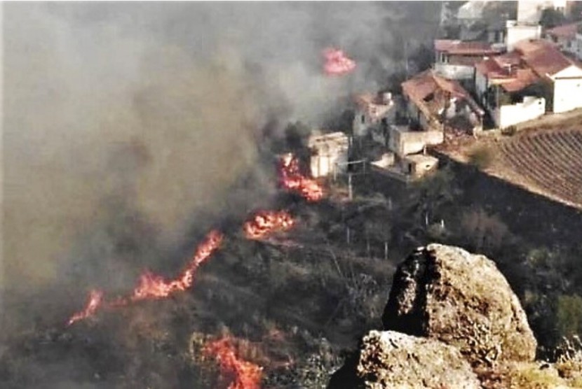 Kobaran api membakar hutan di dekat perumahan warga di El Rincon, Tejeda di Pulau Gran Canaria, Spanyol, Ahad (18/8).