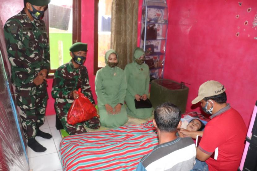 Komandan Batalyon Armed 13/2/1/ Kostrad Sukabumi, Letkol Arm Wahyu Hidayat (duduk) didampingi Ketua Persit Dyana Rose menyerahkan paket sembako kepada warga yang tengah sakit.