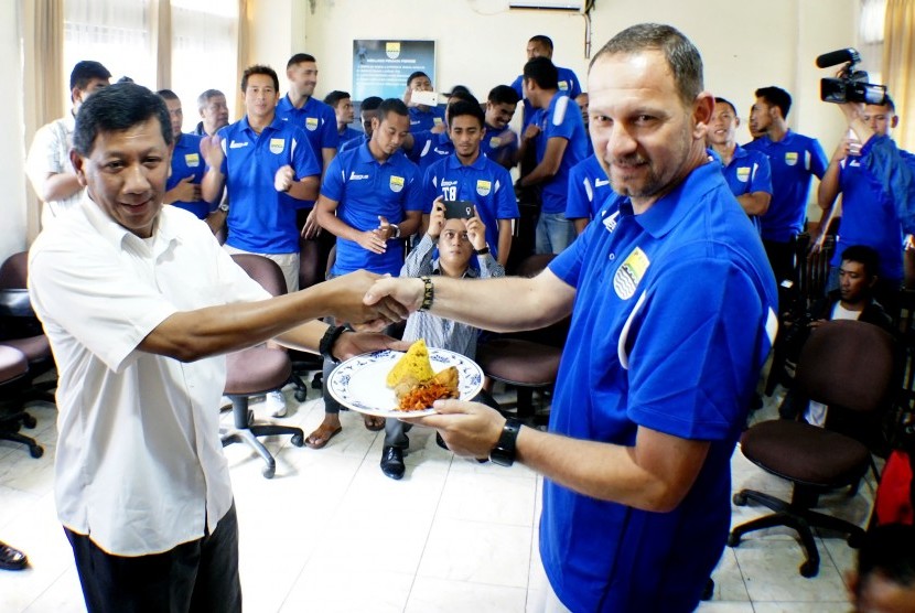 Komisaris PT. PBB Kuswara S Taryono (kiri) memberikan tumpeng kepada pelatih Persib Bandung Dejan Antonic pada perayaan HUT ke-83 Persib Bandung, di Bandung, Jawa Barat, Senin (14/3). 