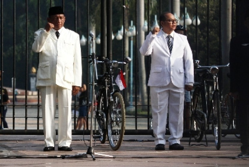 Komunitas sepeda dengan memakai kostum Soekarno dan Bung Hatta mengikuti upacara bendera di kawasan Senayan, Ahad (17/8). 