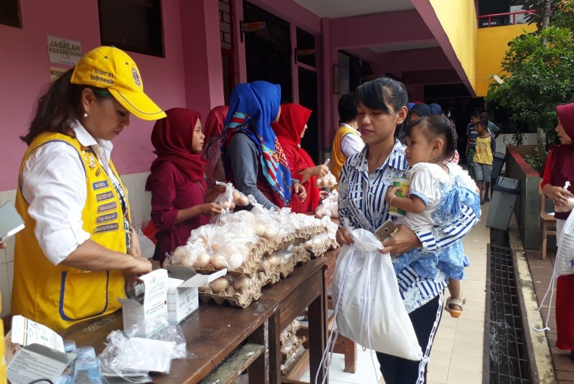 Korban banjir Jakarta menerima bantuan sosial dari organisasi Lions Club di SDN 22, Pejaten Timur, Pasar Minggu, Jakarta Selatan, Ahad (26/1).