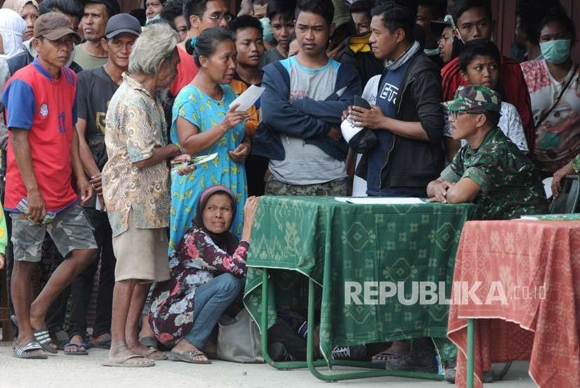 Korban gempa bumi dan tsunami antre untuk mendapatkan bantuan di salah satu posko di Palu, Sulawesi Tengah, Ahad (7/10). 