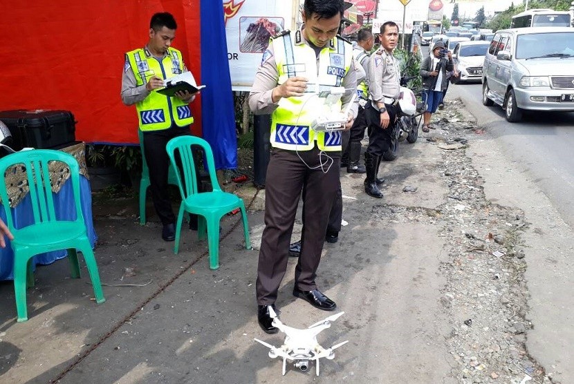 Korlantas Polri AKP Taufik Syahrial menerbangkan drone untuk mengambil gambar untuk bahan penyidikan kecelakaan maut di Jalan Raya Puncak, Turunan Selarong, Cipayung, Megamendung, Kabupaten Bogor, Ahad (23/4). 