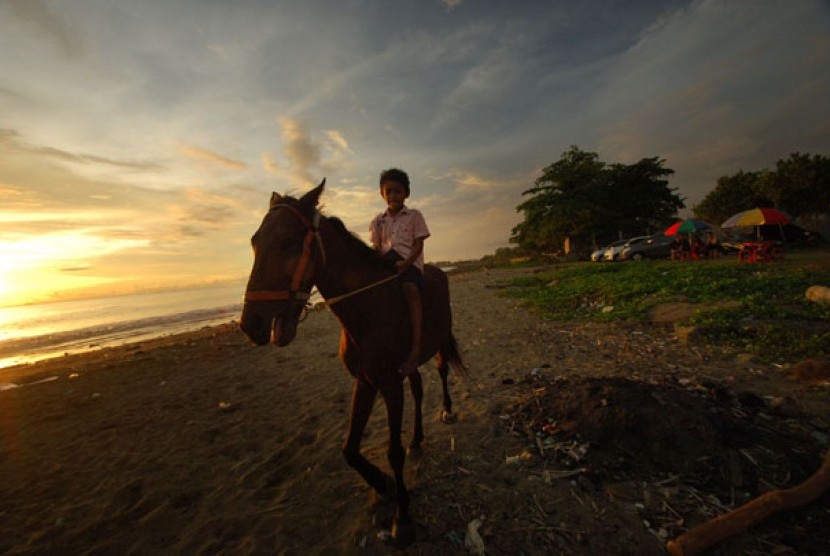KUDA PANTAI PADANG. Anak-anak menunggangi seekor kuda yang disewakan di kawasan pantai Purus, Padang, Sumbar, Senin (29/4). 