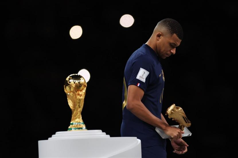  Kylian Mbappe dari Prancis terlihat dibenci saat melewati trofi Piala Dunia setelah memenangkan sepatu emas saat upacara penghargaan setelah Final Piala Dunia FIFA 2022 antara Argentina dan Prancis di Stadion Lusail, Qatar,  Ahad (18/12/2022).