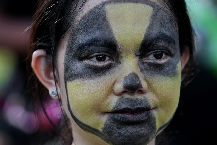 A child with her face painted with nuclear signage